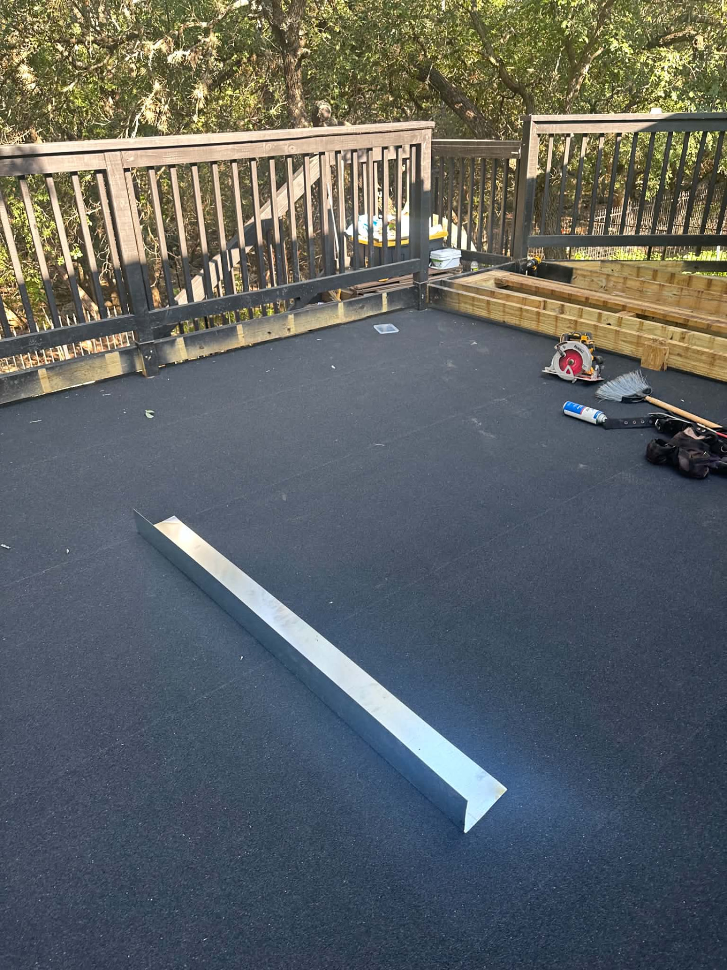 Dark outdoor surface covering beside railings and exposed framing