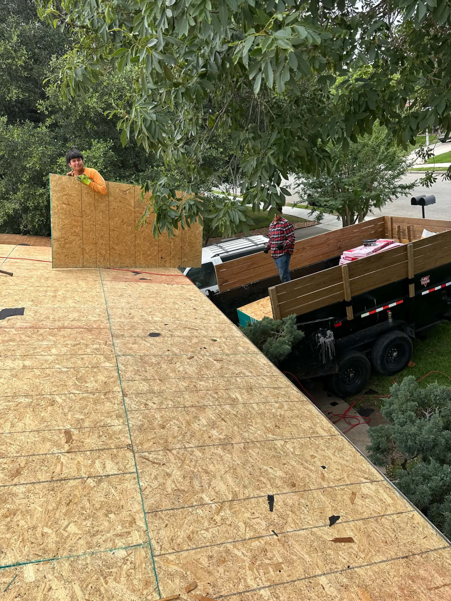 Crew member handling a wood decking panel at the roof edge