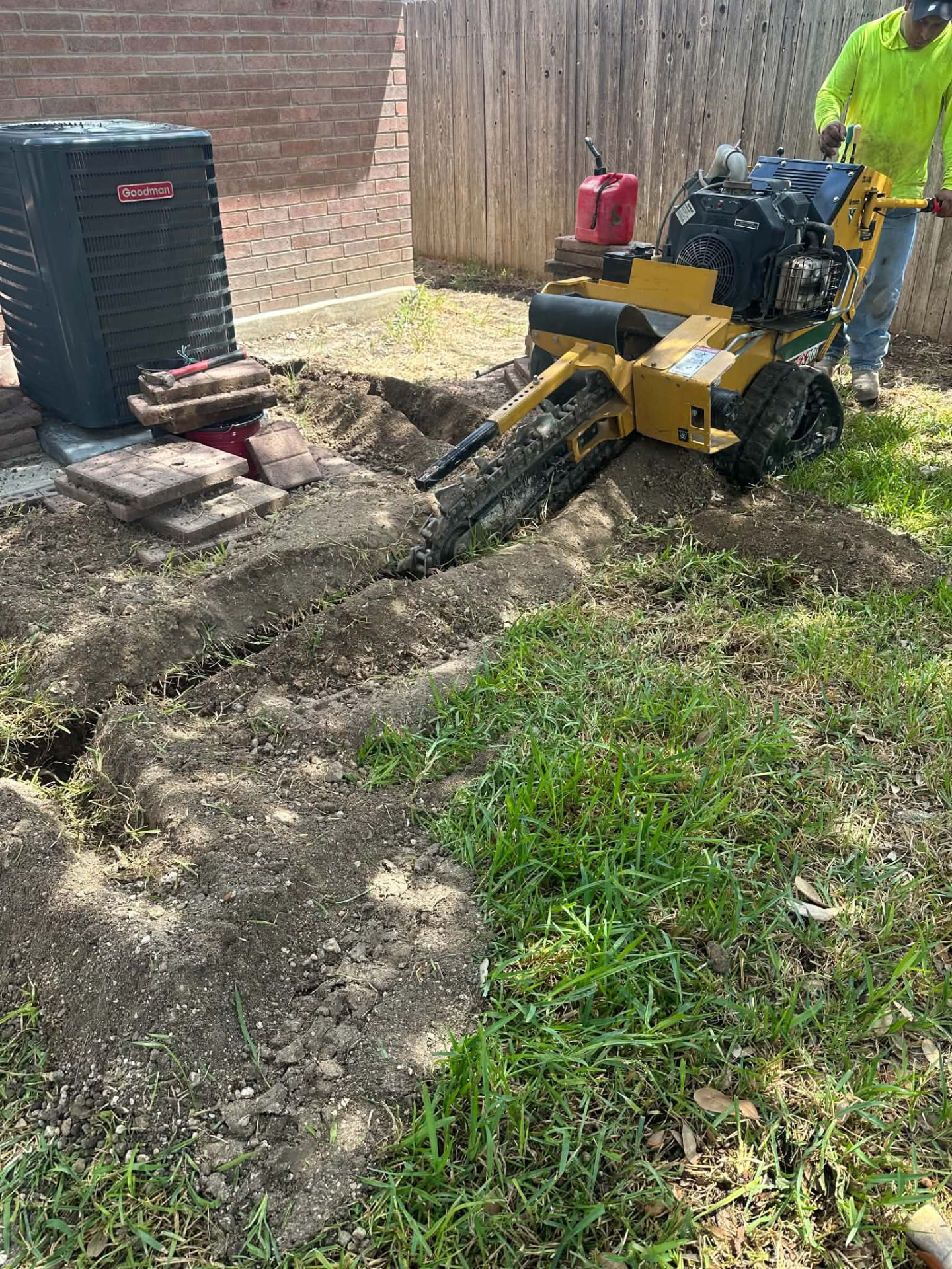Franco crew member operating a walk-behind trencher in a backyard
