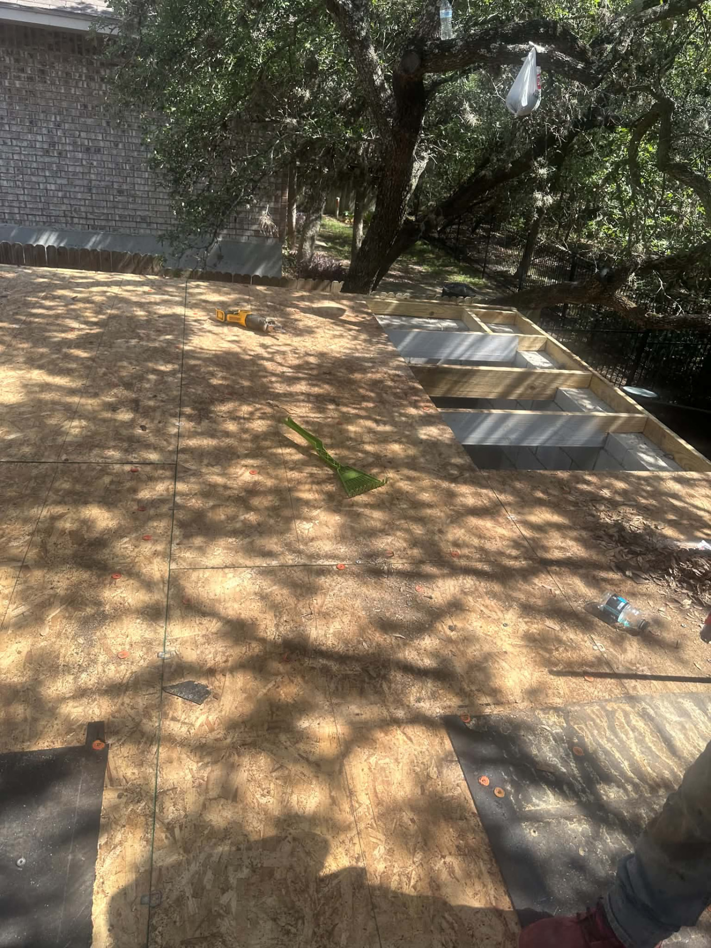 Wood panel decking beside exposed edge framing during roofing work