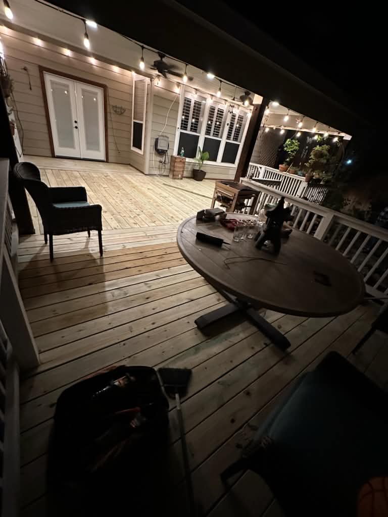 Wide evening view of the finished deck beside the house with string lights