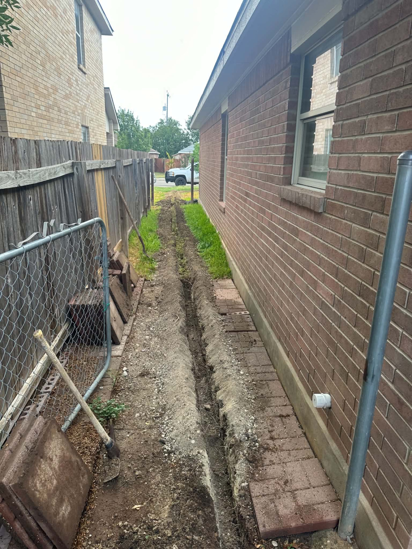 Open trench dug along the side of a brick home