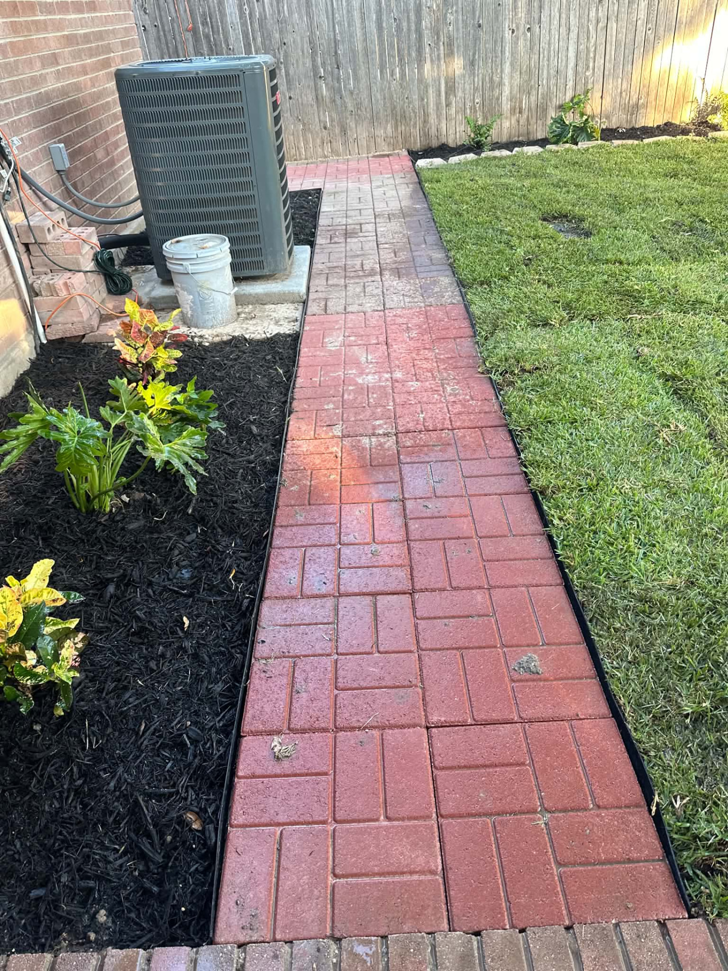 Finished red paver walkway beside a mulched garden bed and lawn