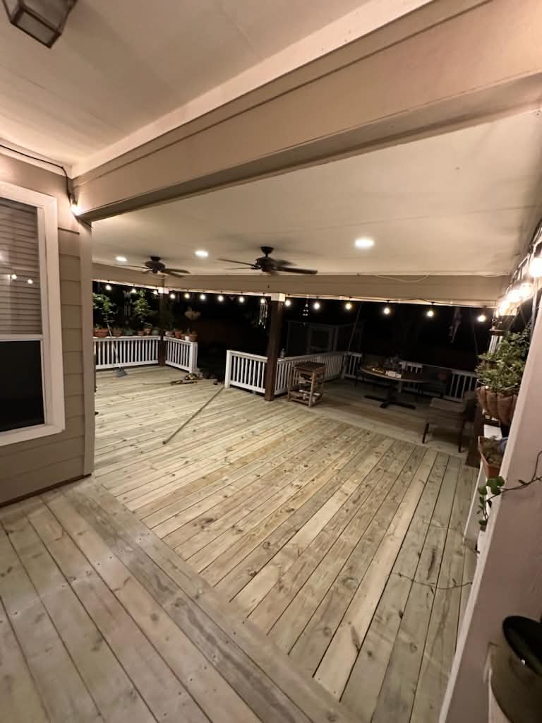 Resurfaced deck under a covered patio with ceiling fans and string lights